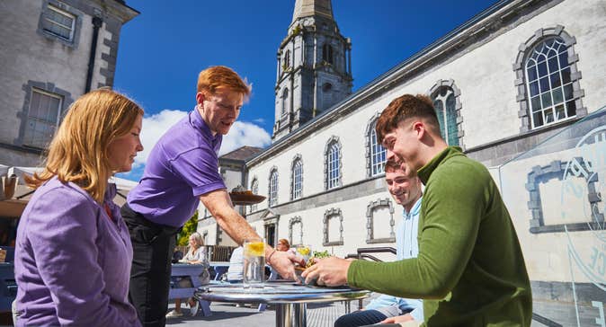 A waiter serving food to a table of three at the Bishop's Palace Café in Waterford city.