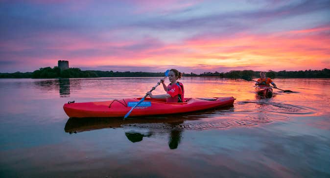 Two people kayaking on Lough Oughter in County Cavan and watching the sunset