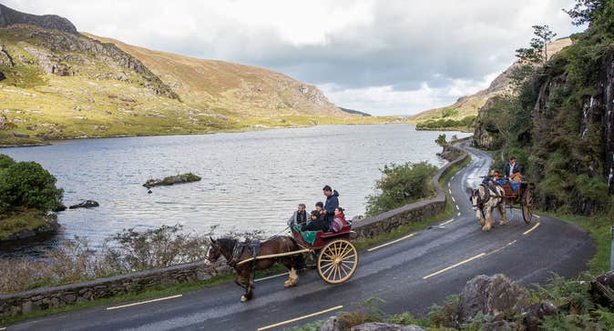 Two pony and carts filled with people travelling along a road in Killarney National Park in County Kerry.